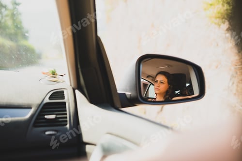 Preview: View of a young woman on the rearview mirror of a car
