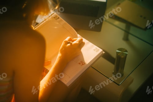 Preview: Caucasian woman making notes at home office.