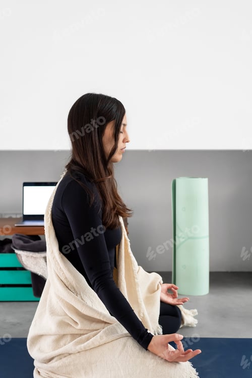 Preview: Woman with eyes closed practicing mindfulness and meditating during yoga practice at home
