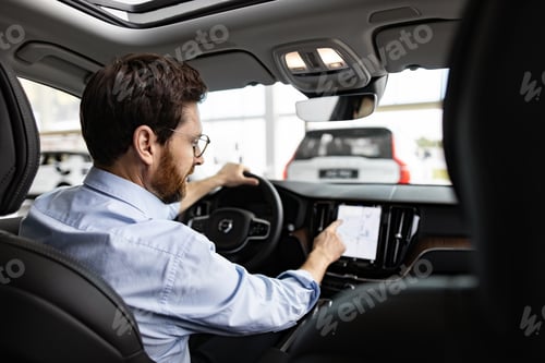 Preview: Businessman using touchscreen inside car at dealership