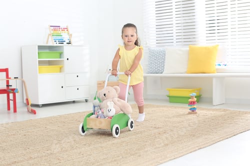 Preview: Cute little girl playing with toy walker at home