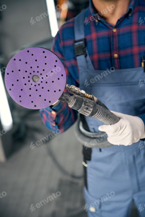 Mechanic Holding Sander Tool in Auto Body Shop