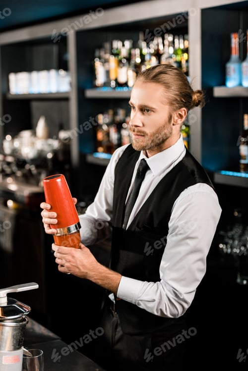 Preview: Handsome barman mixing cocktail in shaker