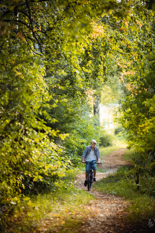 Preview: Boy rides the bike in the autumn forest