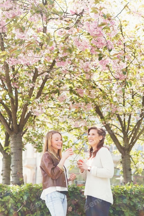 Preview: Female friends holding coffee while standing in park