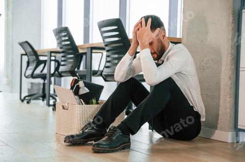 Preview: Depressed, sitting on the floor. Unemployed man is with personal belongings after being fired