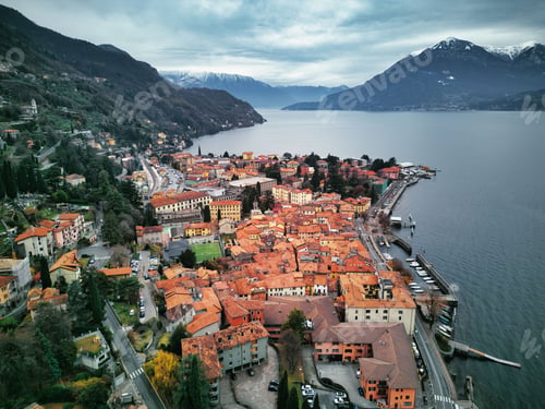 Preview: Drone view of Lake Como surrounded by a town and mountains in the evening in Italy