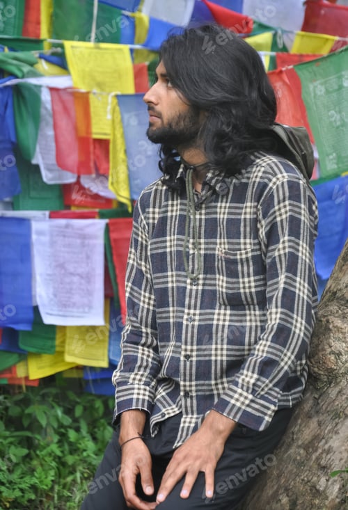Preview: A good looking male tourist looking sideways while posing against Buddhist prayer flags
