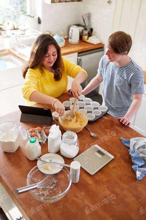 Preview: Young Downs Syndrome Couple Baking Cupcakes In Kitchen At Home