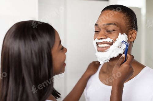 Preview: Caring Young Black Woman Helping Her Boyfriend With Shaving Face