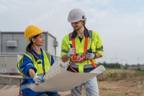 Visualização: Engenheiro masculino e feminino segurando a planta e discutindo a inspeção da turbina eólica no parque eólico