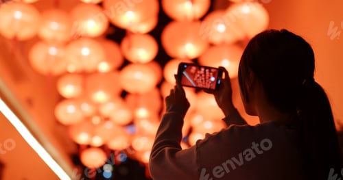 Preview: Woman take photo on cellphone under red lantern