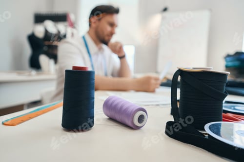 Preview: Man couturier works at table in a sewing workshop
