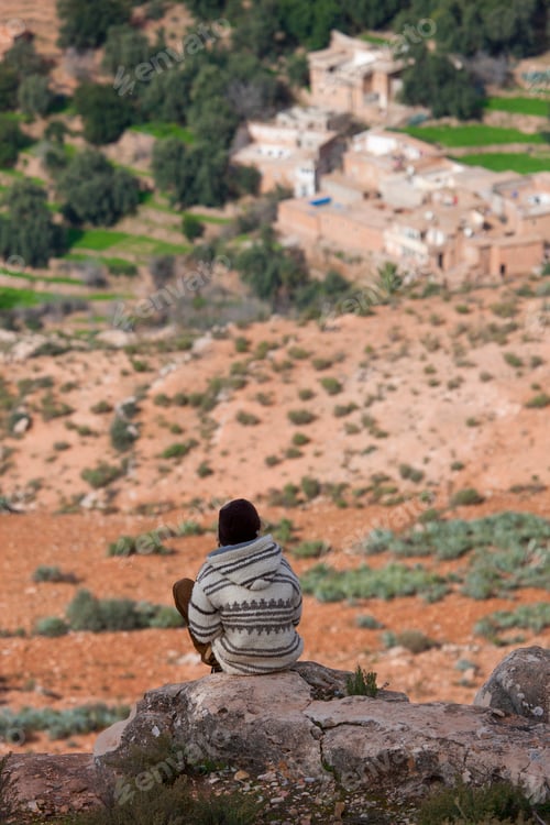 Preview: Rear view of man sitting on rocks above valley, Atlas Mountains, Morocco