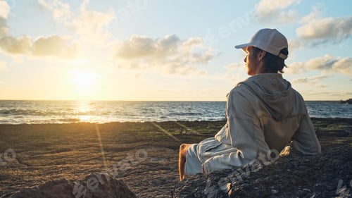 Preview: Man on a beach is looking distance during beautiful summer sunset.