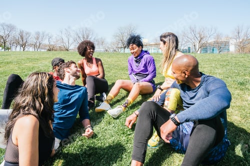 Preview: Group of runners in a park lying on the grass. Talking and laughing.