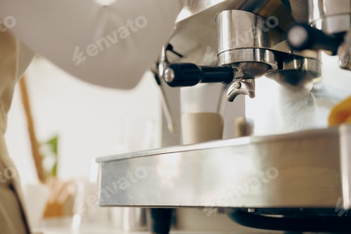Preview: Close up of female barista making coffee in a coffee machine while working in cafe