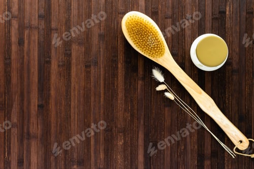 Preview: On a dark wooden table, a jar of cream, a massage brush and dried flowers. Anti-cellulite body care.