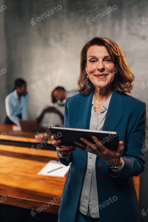 Visualização: Empresária sênior com tablet no escritório corporativo sorrindo para a câmera