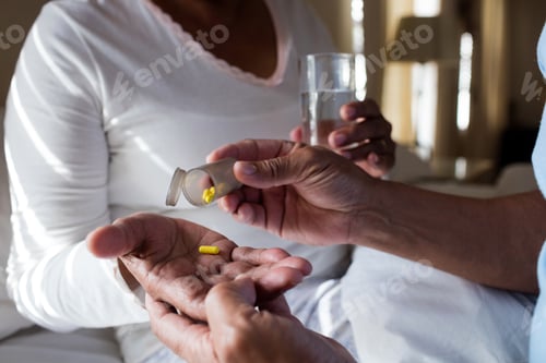 Preview: Senior man giving senior woman to medicine in bedroom