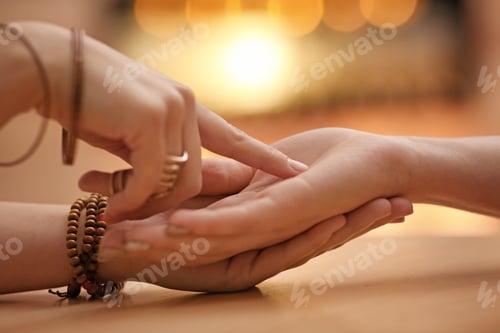 Preview: Chiromancer reading lines on woman's palm at table, closeup
