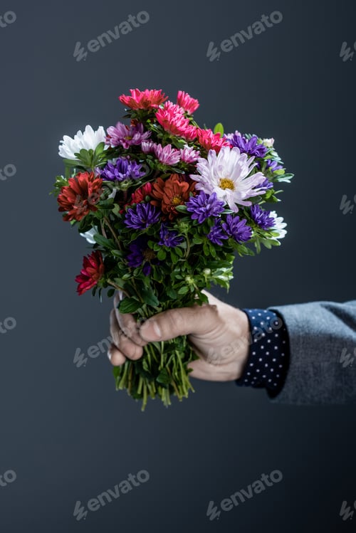 Preview: Cropped shot of man in suit holding a beautiful bouquet of colorful flowers