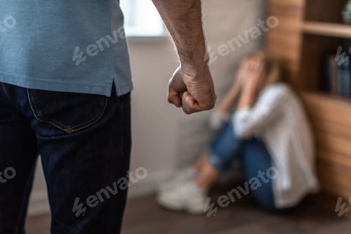 Preview: Scared crying mature caucasian woman covers face sits on floor and afraid of aggressive man with