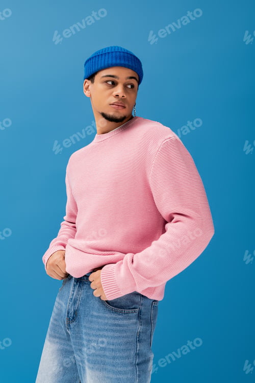 Preview: Fashionable young man poses confidently against a vibrant blue background