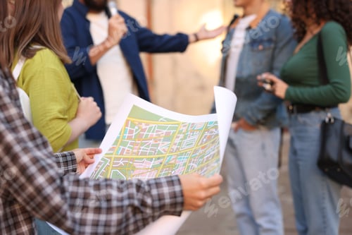 Preview: Guide with microphone and group of tourists on city street during excursion, selective focus
