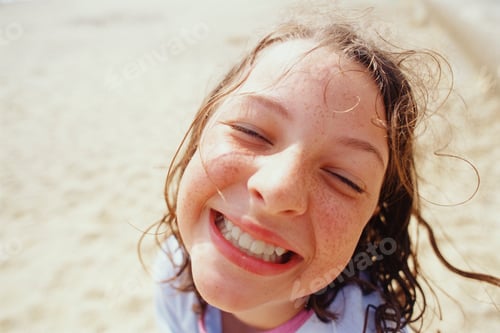 Preview: A young girl with a wide grin, eyes half closed, and wet hair outside in the rain.