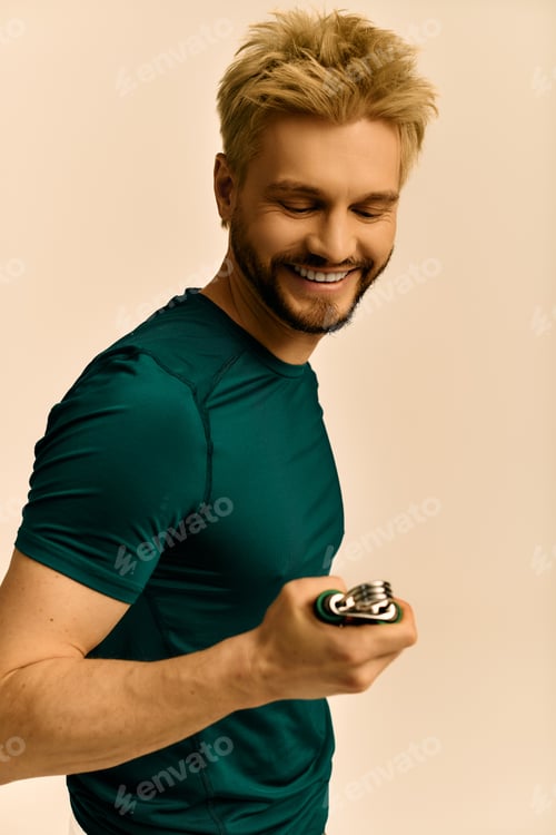 Preview: Handsome young man smiling while holding a stylish gadget in a soft colored studio setting