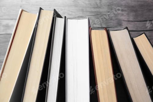 Preview: Collection of different books near wooden wall, closeup