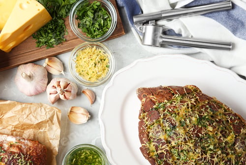 Preview: Loaves of tasty homemade garlic bread with cheese and herbs on grey table, flat lay