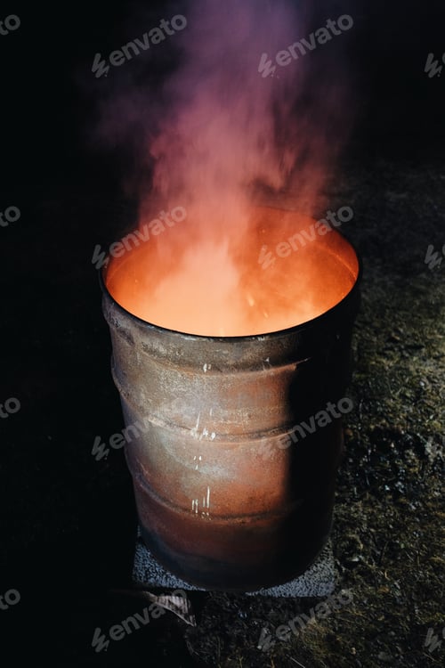 Preview: fire burning inside a metal barrel at night