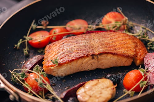 Preview: Tasty salmon fillet with herbs and cherry tomatoes in a pan.