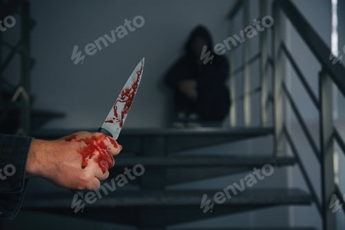 Preview: Man with bloody knife and scared person on stairs indoors, closeup. Dangerous criminal