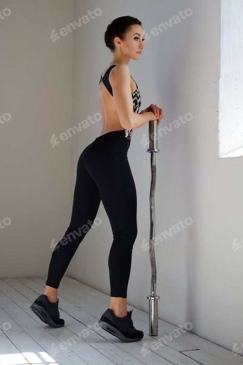 Preview: Woman in Activewear Posing with Barbell Indoors