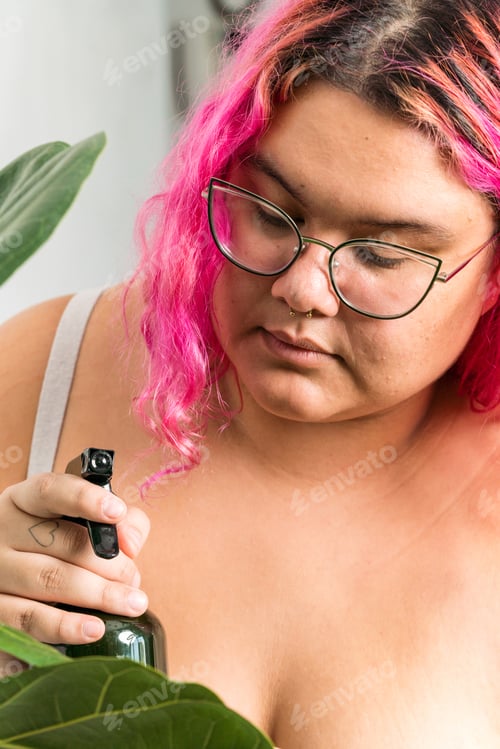 Preview: Woman Spritzing Indoor Plant with Water Indoors