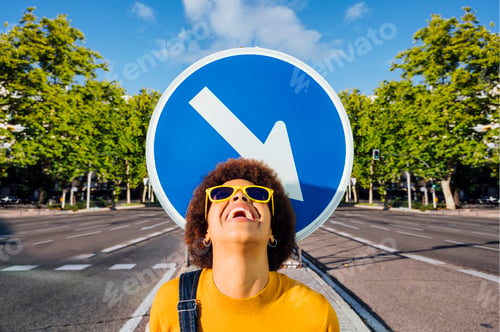 Preview: African American woman with yellow sunglasses next to the road sign