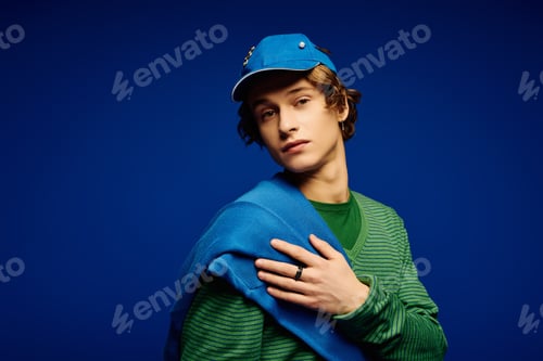 Preview: Young man showcases modern style with vibrant colors against a bold backdrop
