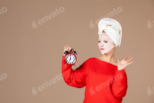 Preview: front view young female with face mask holding clocks on pink background woman moisturizing color