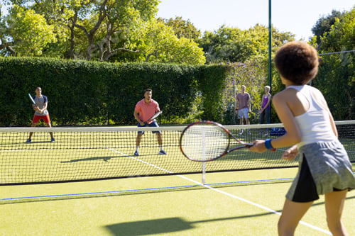 Preview: Happy diverse group of friends playing tennis at tennis court