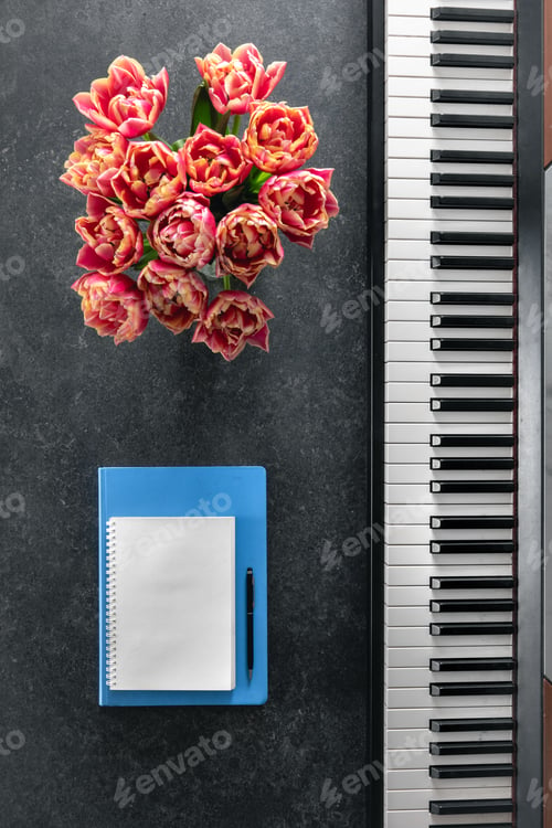 Preview: Piano, bouquet of flowers and notepads on a dark background, top view.