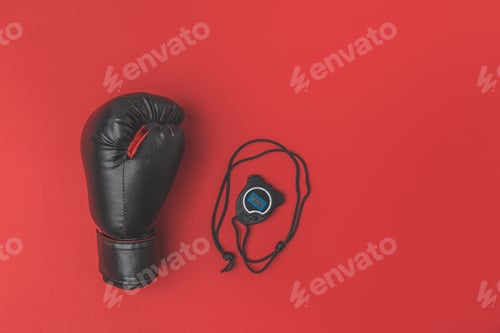 Preview: top view of boxing glove with stopwatch on red tabletop