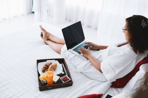 Preview: Young woman sitting on bed with laptop