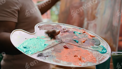 Preview: Painter mixes multiple watercolor paints on a palette to create artwork