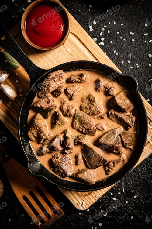 Preview: Delicious fried liver in a frying pan with tomato sauce.