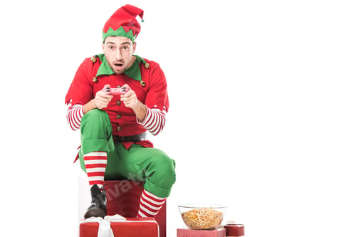 Preview: excited man in christmas elf costume sitting on pile of presents and playing video game isolated on