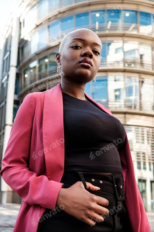 Preview: Young businesswoman posing in front of modern office building