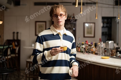 Preview: Blonde young man enjoys coffee in a stylish modern cafe setting